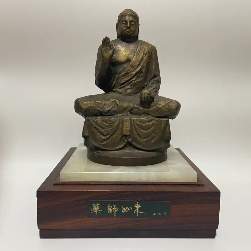 取り扱った品：北村西望作のブロンズ仏像「薬師如来」坐像。「薬師如来　西望作」の銘板が付く木製台座に据えられている