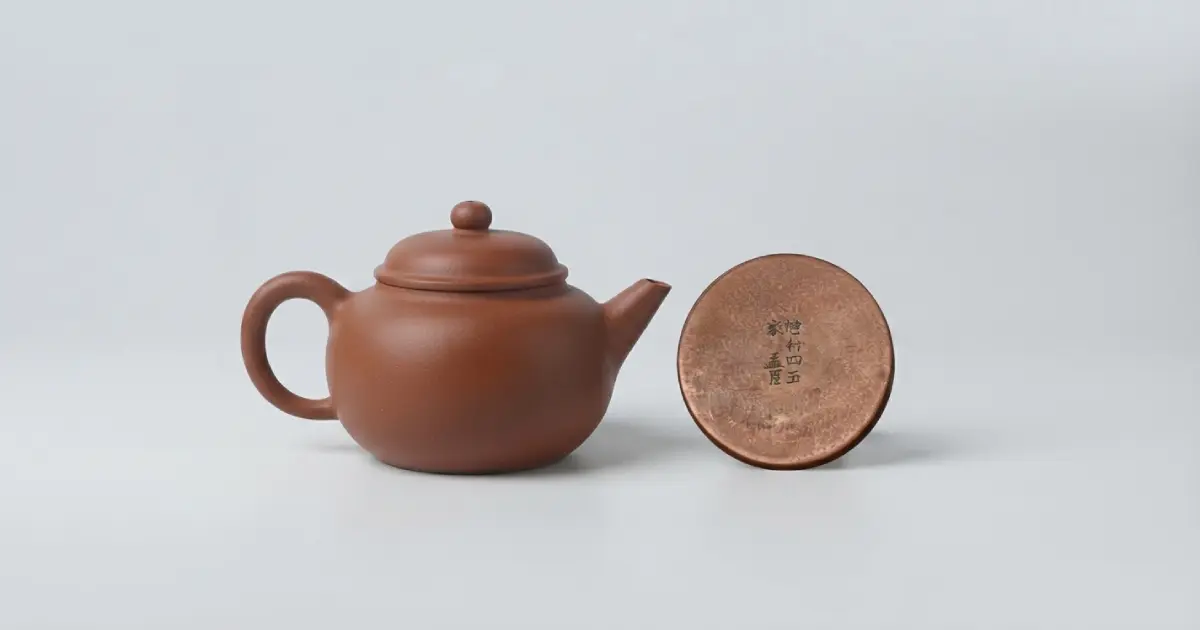 朱泥急須と、その底に刻まれた「孟臣」の銘（部分）