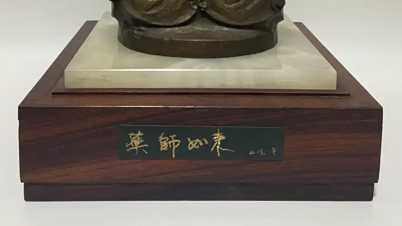 北村西望のブロンズ仏像の木製台座。「薬師如来　西望作」と記された銘板