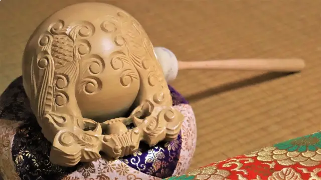 魚鱗と唐草を彫った木魚。金襴の布団に据えられ、撥を添えて伝わった一具