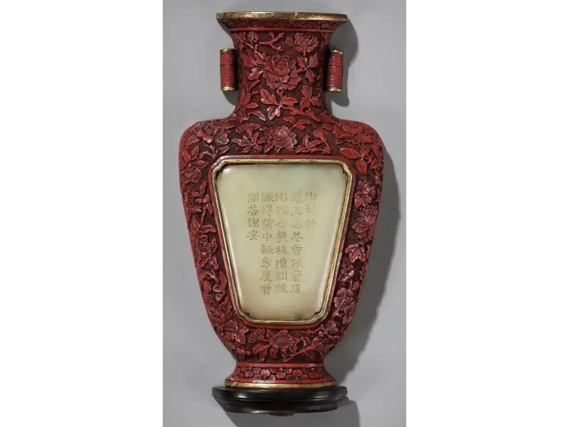 総身に牡丹唐草を彫り、玉（ぎょく）の詩板と金の覆輪を配した堆朱の花瓶。