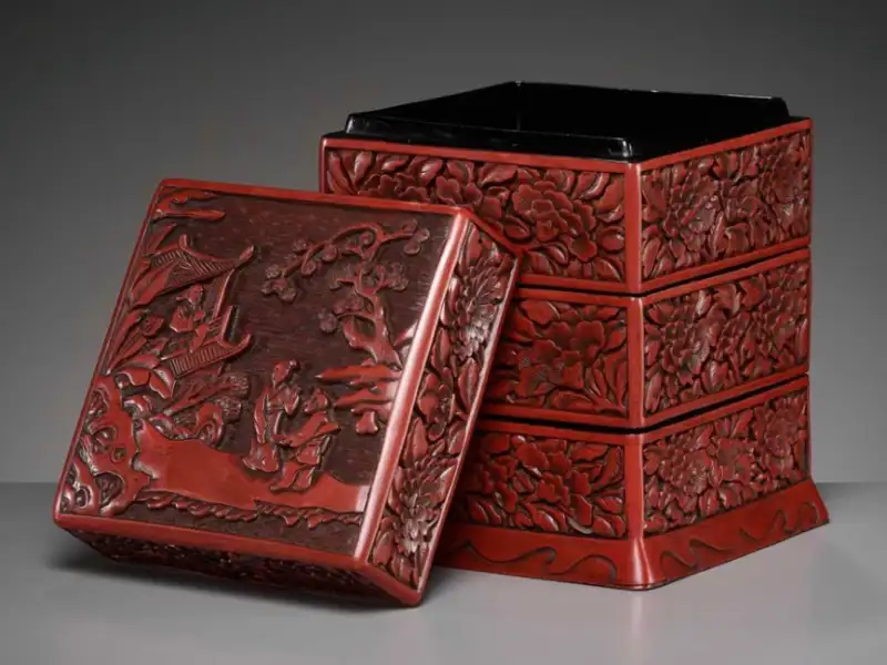 山水人物図を蓋に彫りあらわした堆朱の三段重。側面は牡丹の花卉文、内は黒漆。